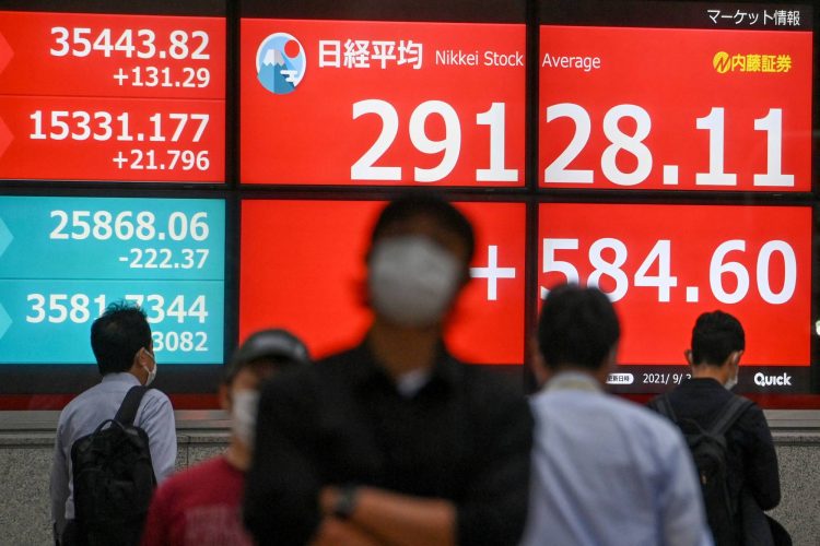 A man walks past an electronic quotation board displaying the closing share prices of the Tokyo Stock Exchange in Tokyo on September 3, 2021. (Photo by Kazuhiro NOGI / AFP)