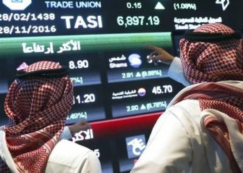 Visitors stand and watch stock movements displayed on large video screens inside the Saudi Stock Exchange, also known as the Tadawul All Share Index in Riyadh, Saudi Arabia, on Monday, Nov.28, 2016. The Tadawul All Share Index advanced 26 percent since Saudi Arabias record-breaking bond sale last month, the most in the world during that period. Photographer Simon Dawson/Bloomberg