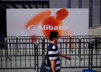 FILE PHOTO: A person walks past a sign of Alibaba Group during the World Artificial Intelligence Conference, following the coronavirus disease (COVID-19) outbreak, in Shanghai, China, September 1, 2022. REUTERS/Aly Song